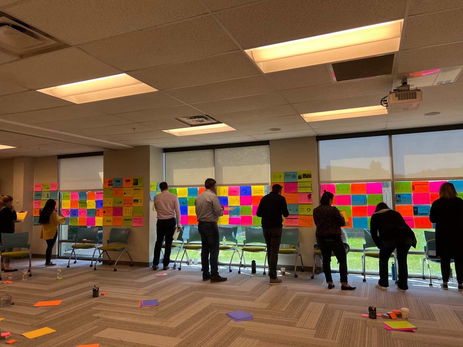 A team working side by side along a long wall of ideas