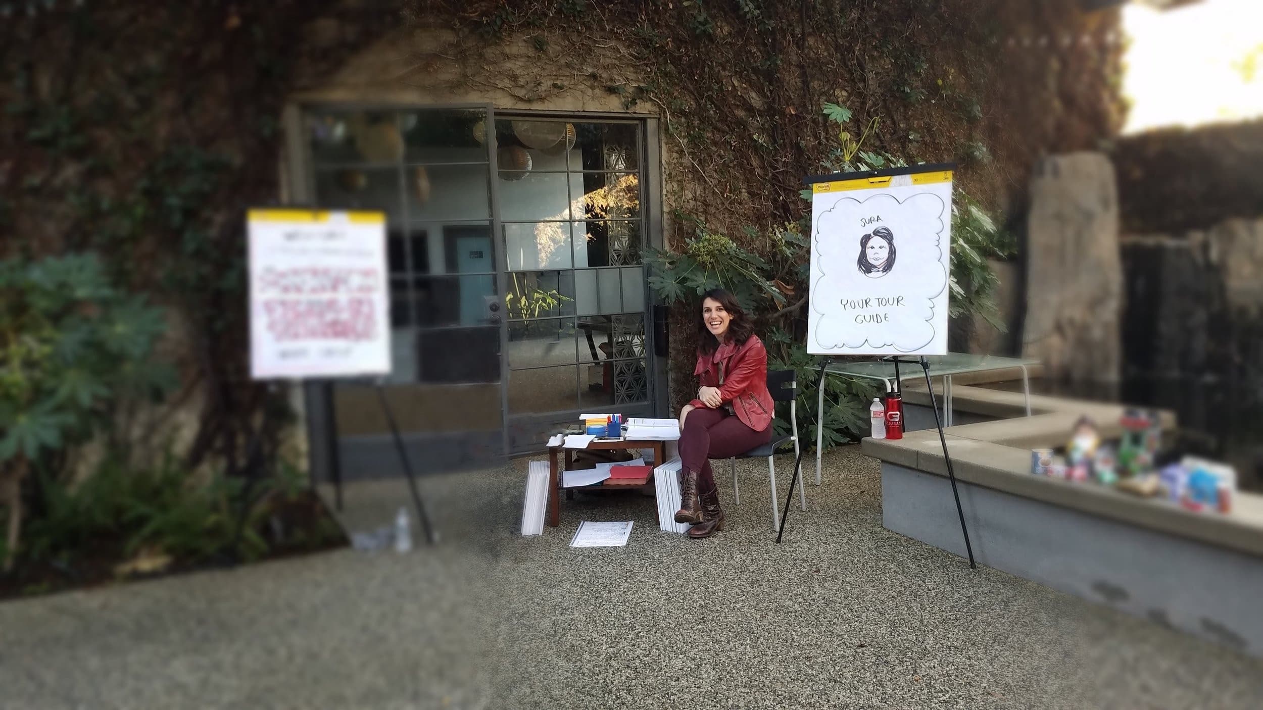 Sura sitting outside beside a flip chart that reads “Sura — your tour guide”