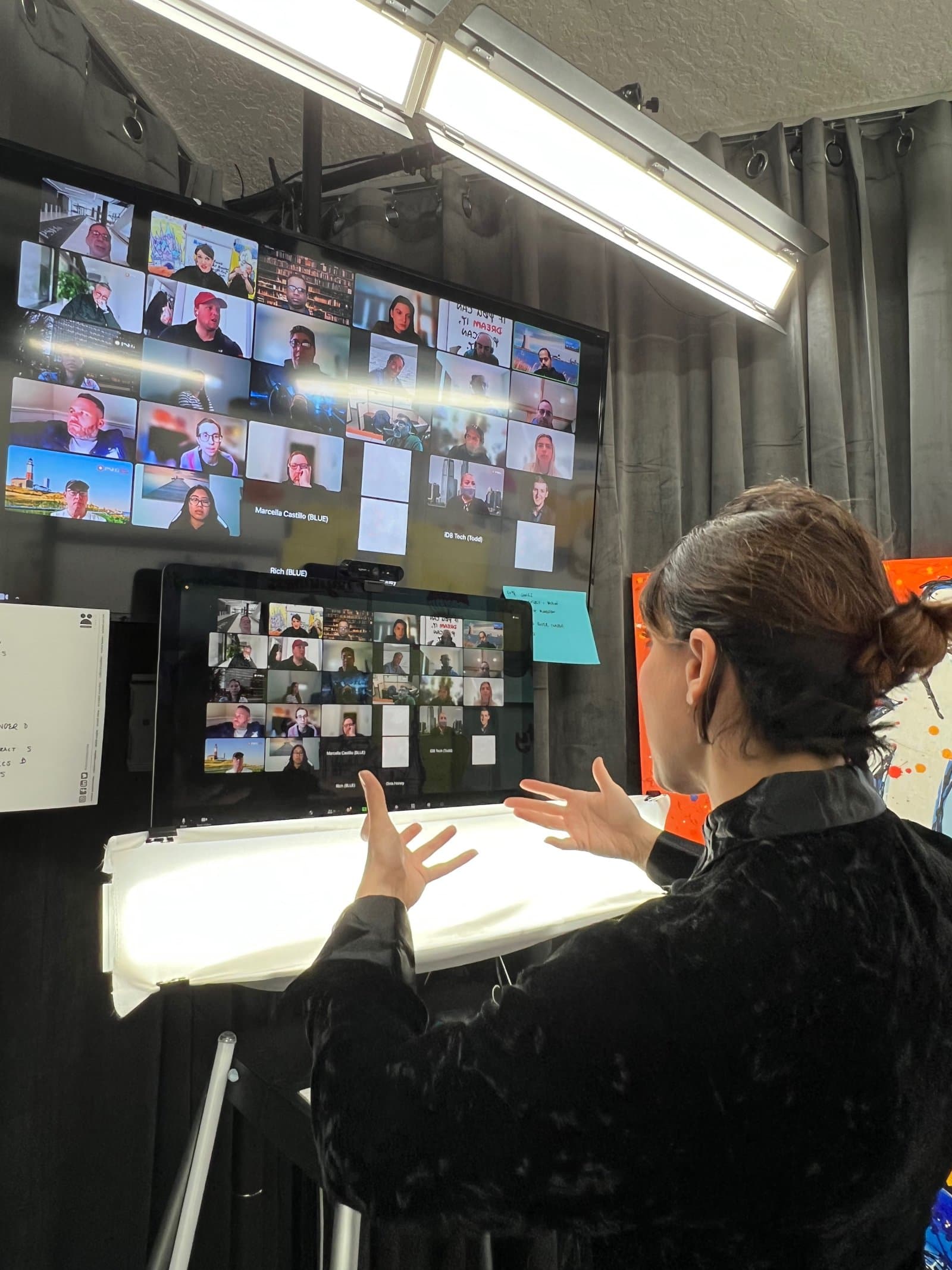 Sura facilitating a virtual session in front of a wall of video-call screens